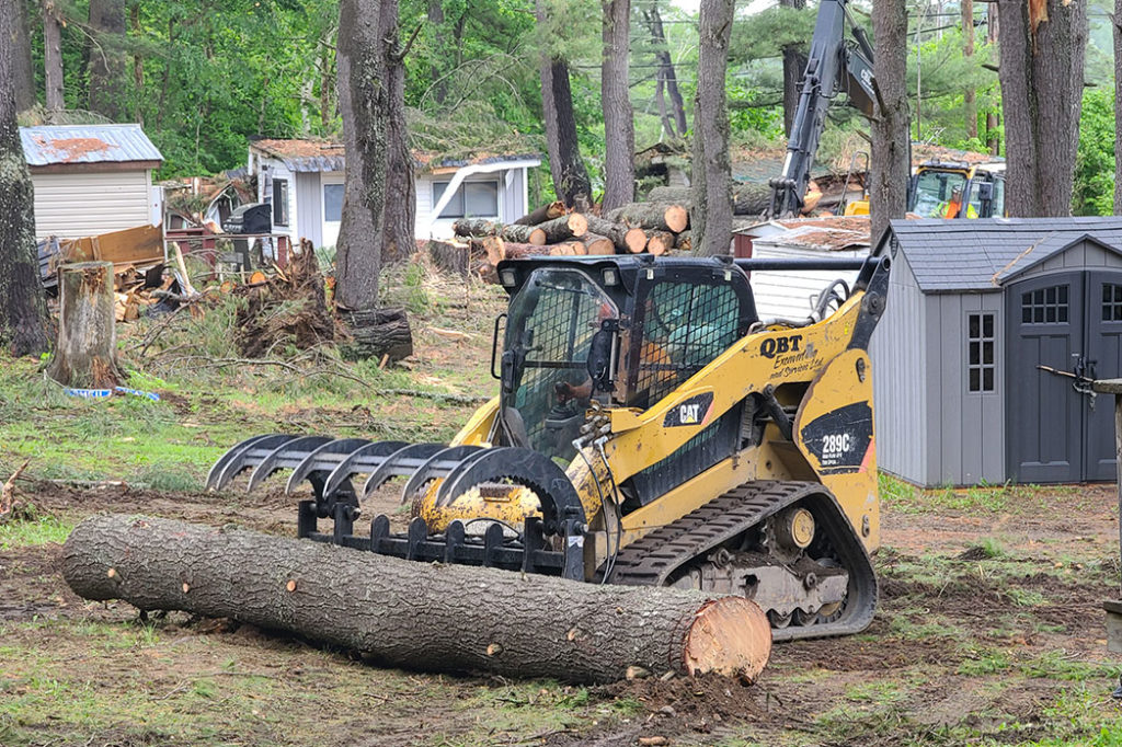 Foley Tree Service team member using equipment to pick up large tree trunk pieces