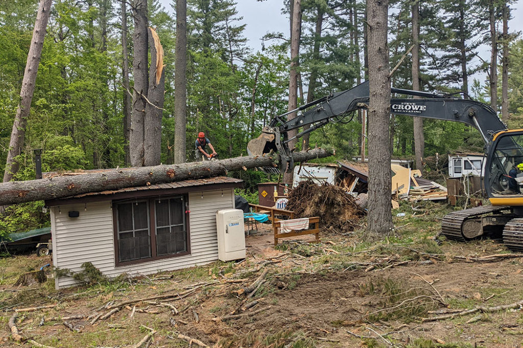 Foley Tree Service team member using chainsaw to cut chunks off for excavation from cottage roof